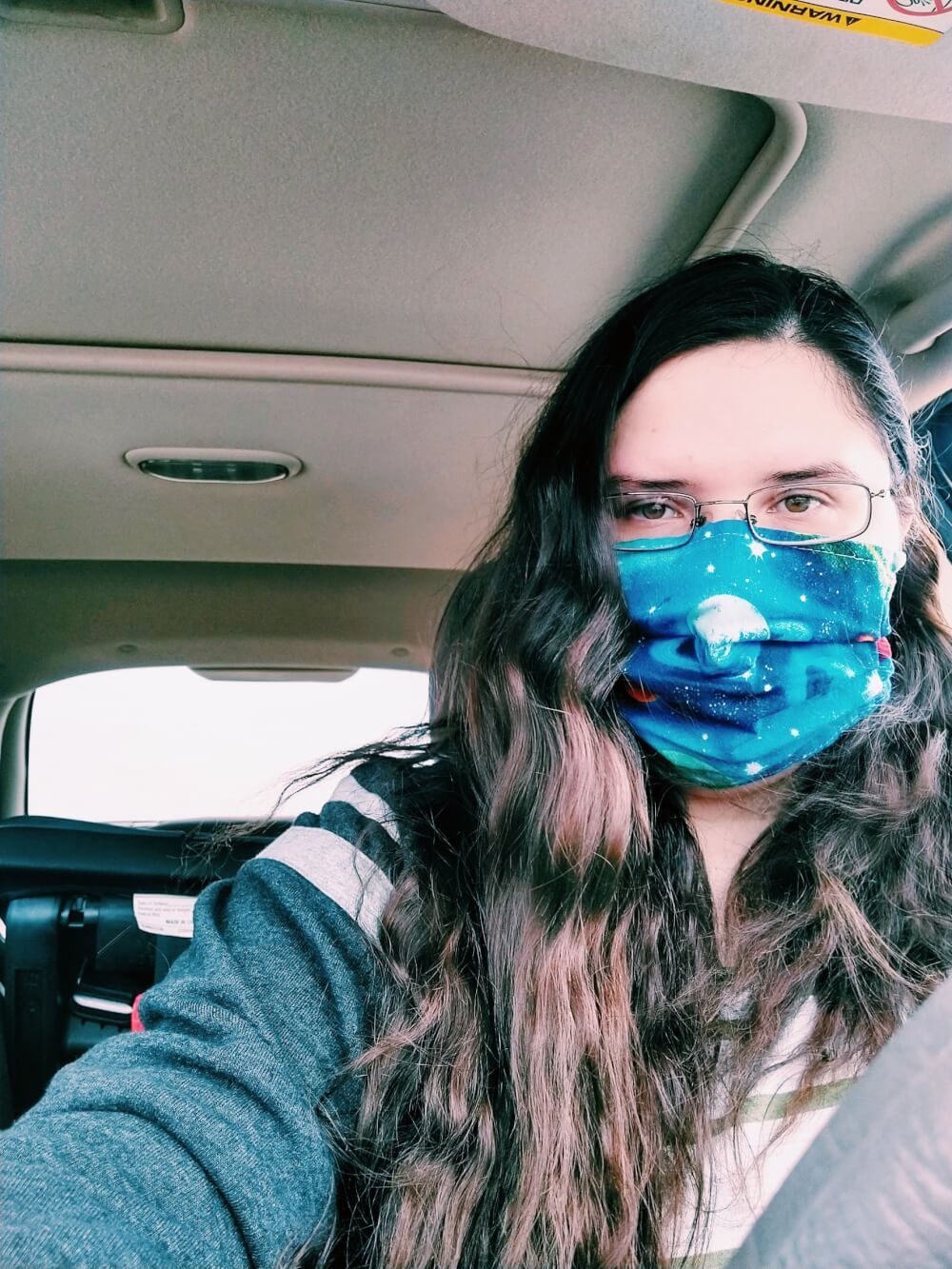 Selfie of me wearing a planetary mask, with wavy hair, in my car
